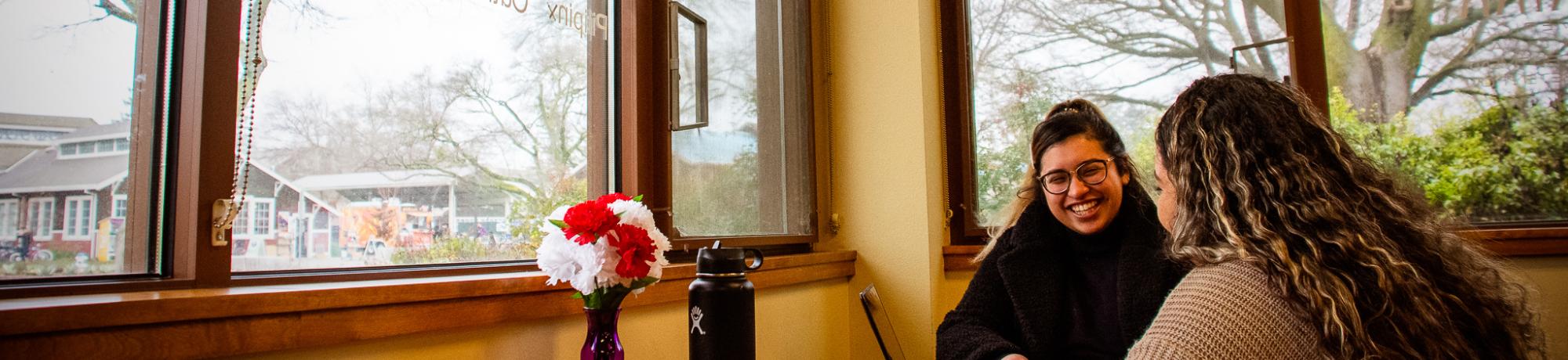 image of 2 students talking to each other by a window